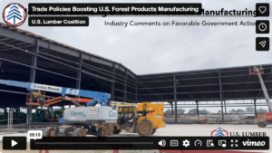 Partially constructed industrial building with cranes, lifts, and construction equipment. Banner at top discusses U.S. forest products manufacturing and government actions.
